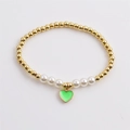 Detail of beaded bracelet with gold metal beads, white pearls, and green heart pendant - Green