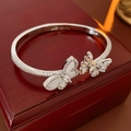 Detail van zilveren vlinderarmband met zirkonia op een houten sieradendoosje - Zilver