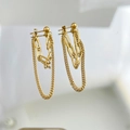 Detalle de pendientes de doble cadena dorada con borlas y pernos esféricos sobre blanco - Dorado