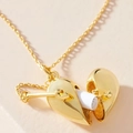 Detail eines offenbaren goldenen Herzmedaillons mit kleiner Papierrolle im Inneren - Gold Herz Medaillon