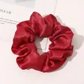 Detailed view of vibrant red silk satin scrunchie with elegant pleated fabric texture - Red