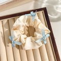 Beige floral lace scrunchie with blue ribbons on a jewelry display tray - White Band Blue Bow