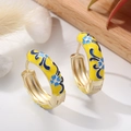 Detailed view of yellow enamel hoop earrings with blue floral patterns on a stone background - Yellow Base Blue Flower
