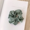 Green satin scrunchie hair tie with iridescent finish on a rustic wooden table - Pearly Satin Green
