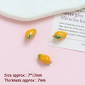 Detail view of 7x13mm gold-plated mango pendants with yellow enamel and green leaf - Mango
