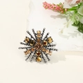 Macro shot of vintage metal flower brooch with amber crystals on white marble - Gunmetal Snowflake Starburst Style