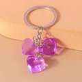 Detalle de dijes de corazón de resina púrpura translúcida en un llavero de metal plateado - Morado
