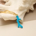 Golden necklace featuring a blue coral pendant set against a white seashell background - Blue