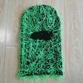 Distressed green and black knitted balaclava mask shown flat on light wood background - One Size / Black and Green Mix