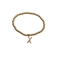Macro detail of gold beaded bracelet with a colorful zircon micro-paved letter X charm - Letter X