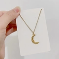 Detailopname van gouden halsketting met maan hanger op witte kaart met fijne schakelketting - Getextureerde Maan