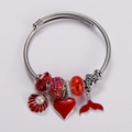 Detailaufnahme eines silbernen Charm-Armbands mit roten Herz- und Muschelanhängern - Rotes Thema Herz Meerjungfrau Schwanz Stil