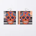 Detail view of orange acrylic skull earrings with colorful floral embossed patterns - Bright Orange with Purple Floral