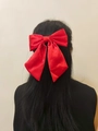 Elegant large red satin bow hair clip accessory worn on long black hair for women - Spring Clips / Red