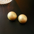 Detail of matte gold spherical stud earrings on black leather with glass accents - Gold Circles