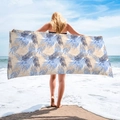 Microfiber beach towel with tropical palm leaf print being displayed on a sandy beach - Blue Yellow Palm