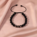 Detailed shot of black beaded adjustable bracelet with galaxy beads on pink satin fabric - Black Starry Texture / Obsidian Luminous Black
