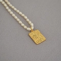 Close-up of freshwater pearl necklace featuring a gold rectangle flower coin pendant - Daisy Flower