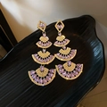 Detailopname van luxe vergulde hangende oorbellen met paarse strass en kwastjes - Roze Paars (Zilveren Naald)