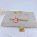 Macro view of gold-plated heart pendant with pink enamel detail on beige stone plates - Pink White Gold Heart