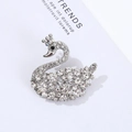 Detailed view of luxury silver swan brooch with crystals on a fashion magazine background - Crown Swan