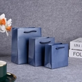 Three blue paper gift bags in different sizes with rope handles on a textured background - 10x5x10cm / Pearlescent Lake Blue