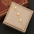 Dettaglio ravvicinato della collana con tre pendenti a farfalla opaca e nappe dorate - Collana