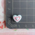 Macro detail of a 1.3cm blue and pink heart-shaped resin accessory on a ruler - Blue and Pink