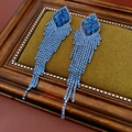 Macro-detail van lange blauwe zirkoon kwastjes oorbellen met zilveren naald op groen fluweel - Blauw