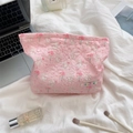 Pink quilted cosmetic bag with floral rabbit pattern on bed with makeup accessories - Bouquet Rabbit