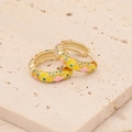 Macro view of gold hoop earrings with yellow, pink and green enamel floral patterns - Yellow