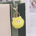 Close-up of yellow plush coal ball keychain with big eyes on a green luxury handbag - Gold Chain Clasp / Yellow