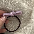 Close-up of a pink ceramic texture bow hair tie held against a beige woven background - Acetate Bow-Purple