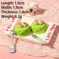 Macro shot of miniature green mousse cakes with roses on a tray and strawberry teacup - Green Rose Cake