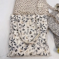 Détail à plat d'un sac cabas en toile fleurie avec une étiquette rectangulaire cousue - Fleur à l'Encre sur Fond Beige