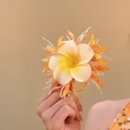 Detailaufnahme einer frischen weiß-gelben Plumeria-Stoffblumen-Haarklammer für Damen. - Entenschnabel-Clips / Orange