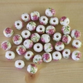 Close-up of white ceramic round beads with pink floral prints on a wood background - No.31-Pink Rose