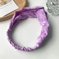Detail of purple paisley twisted headband with elastic band on a decorative background - Purple