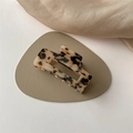 Dettaglio di un mollettone rettangolare in acetato tartarugato su un cuscinetto in pelle - Leopardo Chiaro