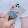Detail of a marble textured phone socket with gold trim on a white smartphone - Gold Round Collapsible Socket Grip / Blue
