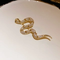 Macro detail of vintage gold snake brooch with crystal pavé and black gemstone eyes - Patterned Snake