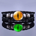 Nahaufnahme von Steampunk Lederarmbändern mit leuchtenden Drachenaugen-Anhängern und Reflexion - Orangegelber Augenstil
