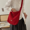 Detailaufnahme der roten Teddy-Plüschtasche mit Lederlogo auf einem Vintage-Stuhl - Burgunderrot