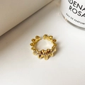 Detalle de anillo de onda dorada con circonitas sobre superficie blanca mínima - Dorado
