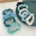 Close-up of 8 colorful satin scrunchies arranged on a tray showing silk texture - Fresh Blue Green