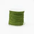 Macro detail of dark green 0.8mm cord neatly wound on a white spool for jewelry making - Color 214 Teal