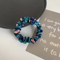 Elastic satin scrunchie in green with pink-orange spots on a clean white desk - Green Leopard