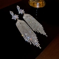Gros plan de longues boucles d'oreilles à pompons avec fleurs en strass - Gland en Pierre Feuille Florale (25#)