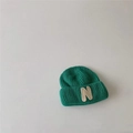 Detailed macro view of the dark green knitted texture and bold letter N patch on the hat - Green