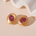 Detalle de pendientes ovalados de oro mate con piedra preciosa magenta y cristales - Rosa